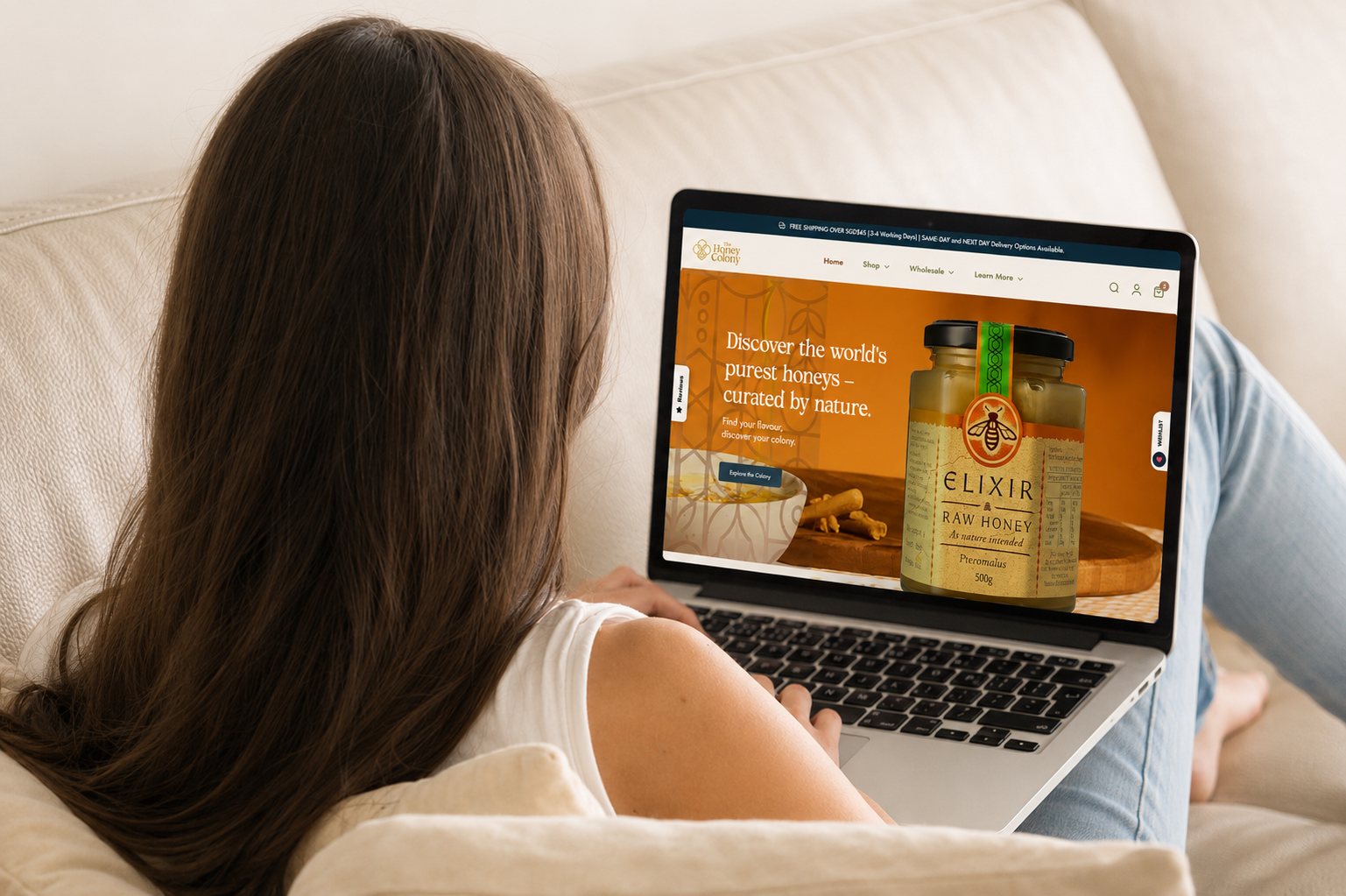 Woman browsing The Honey Colony homepage on a laptop while shopping for natural honey online in Singapore.