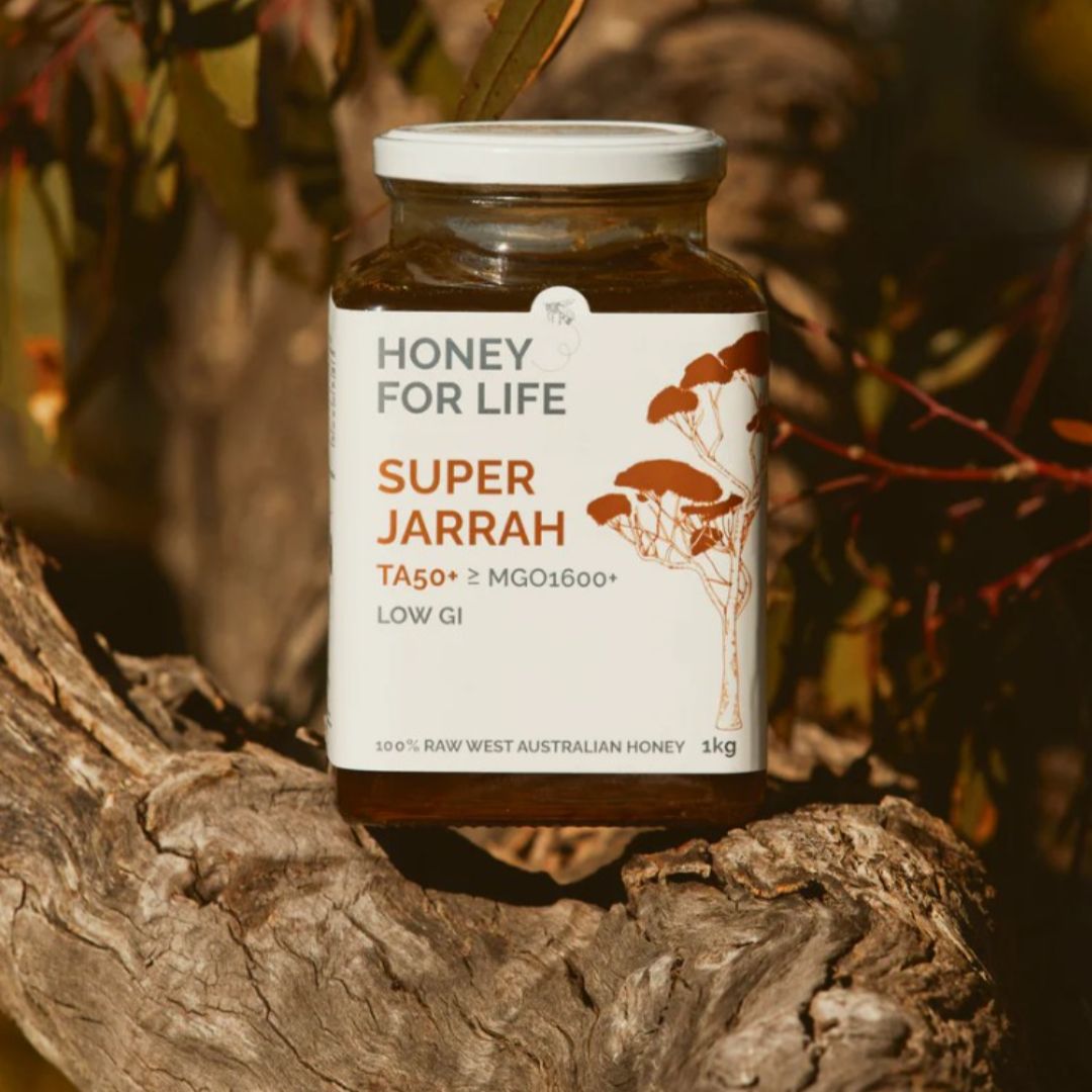 Jar of 'Honey for Life Super Jarrah' honey on a wooden surface with a natural background.