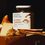 Honey For Life Super Jarrah honey jar with jarrah wood and honeycomb on a dark background