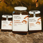 Three jars of 'Honey for Life Super Jarrah' honey on a wooden surface with a natural background.