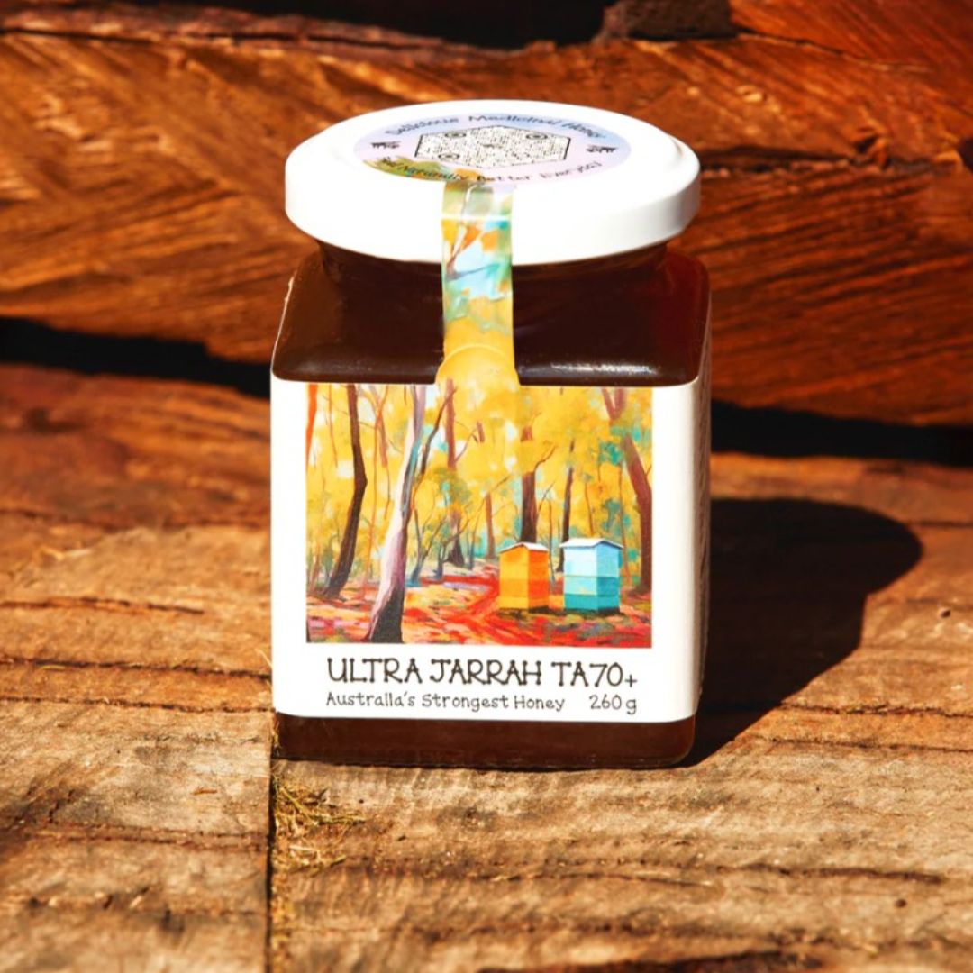 Jarrah honey container with artwork on a wooden surface