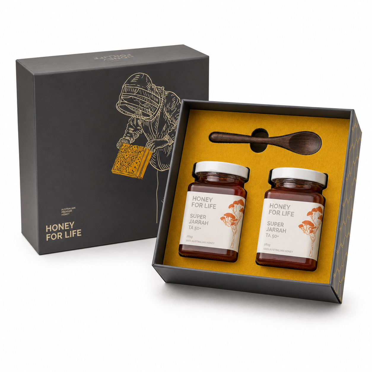 A honey gift set in an open black presentation box with a gold interior, containing two glass jars of honey labeled 'HONEY FOR LIFE SUPER JARABH TA SIP' and a small wooden spoon, shown beside the matching black outer box on a white background.