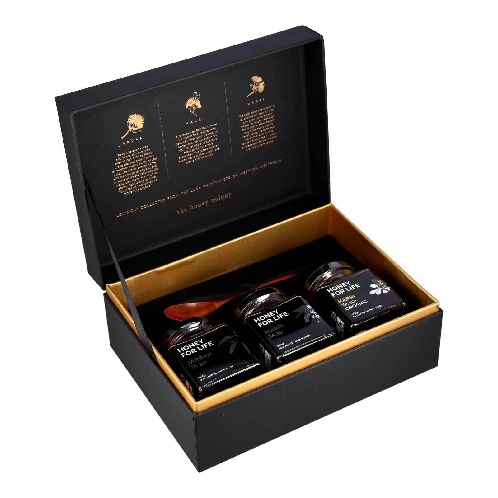 A gift box open to reveal three jars of honey gifts and a wooden spoon, neatly arranged inside a golden inner box.