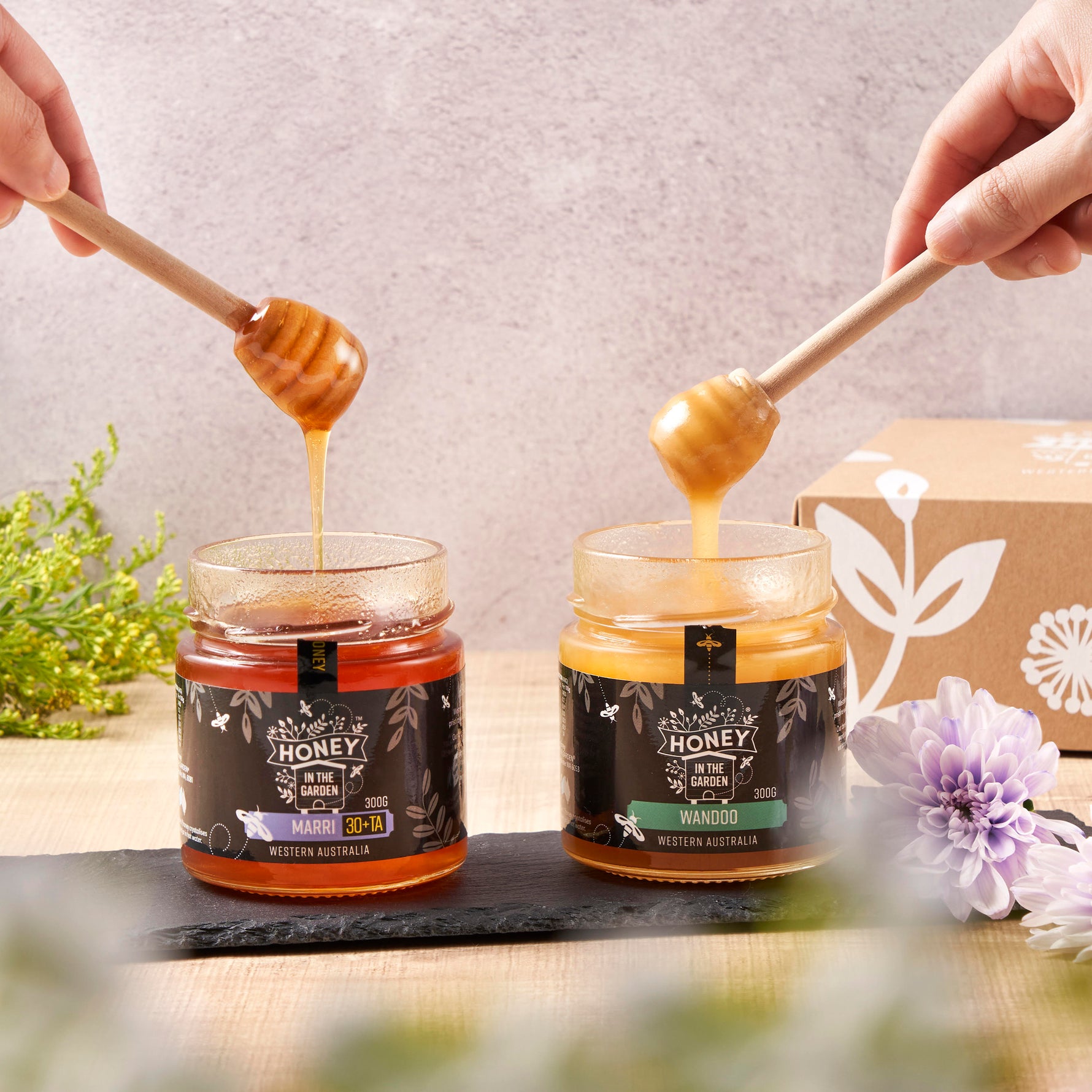 two open jars from the Honey in the Garden gift box with hands holding a dipper above each one